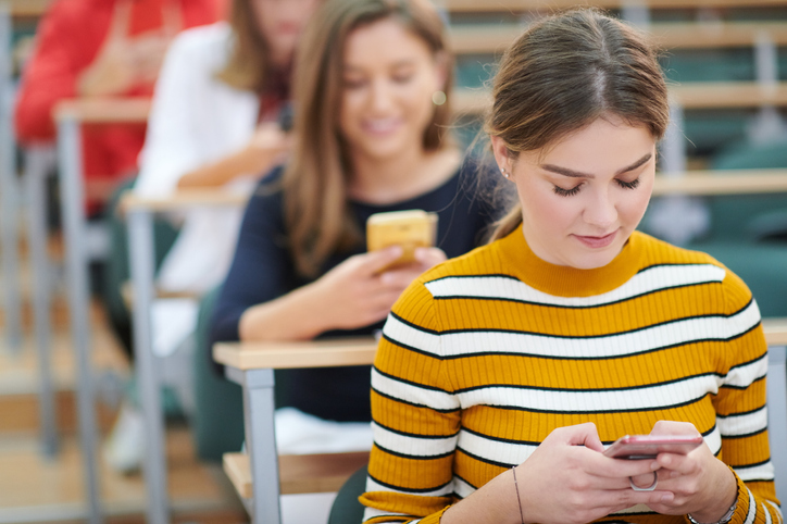 female female students use a smartphone during classroom instruction